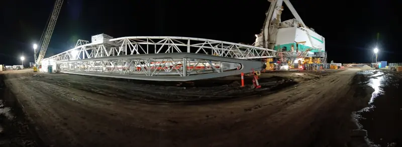 Panorama of a dragline boom on stands under floodlights at night