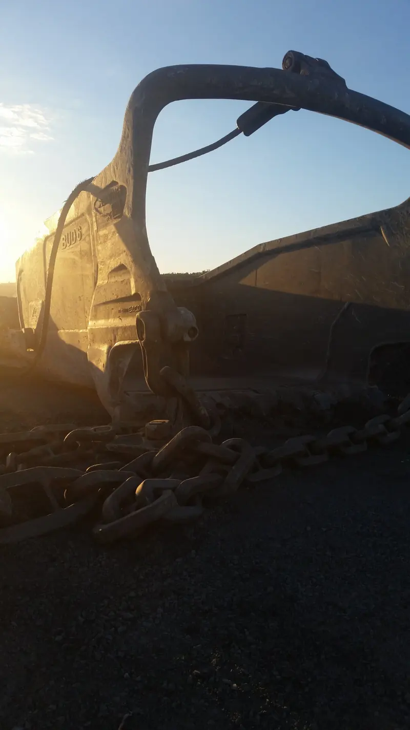 Dragline bucket and drag chains backlit by the setting sun