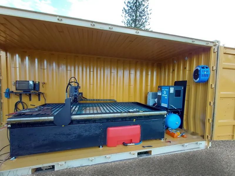 Marquee CNC plasma cutting table, controller and air compressor set up inside a shipping container