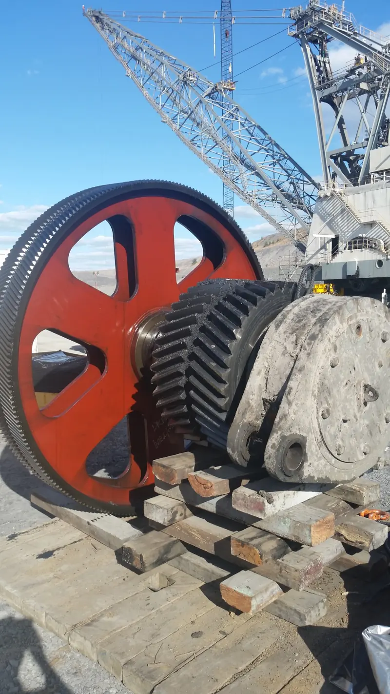 New bull gear and pinion set staged on timber in front of a dragline